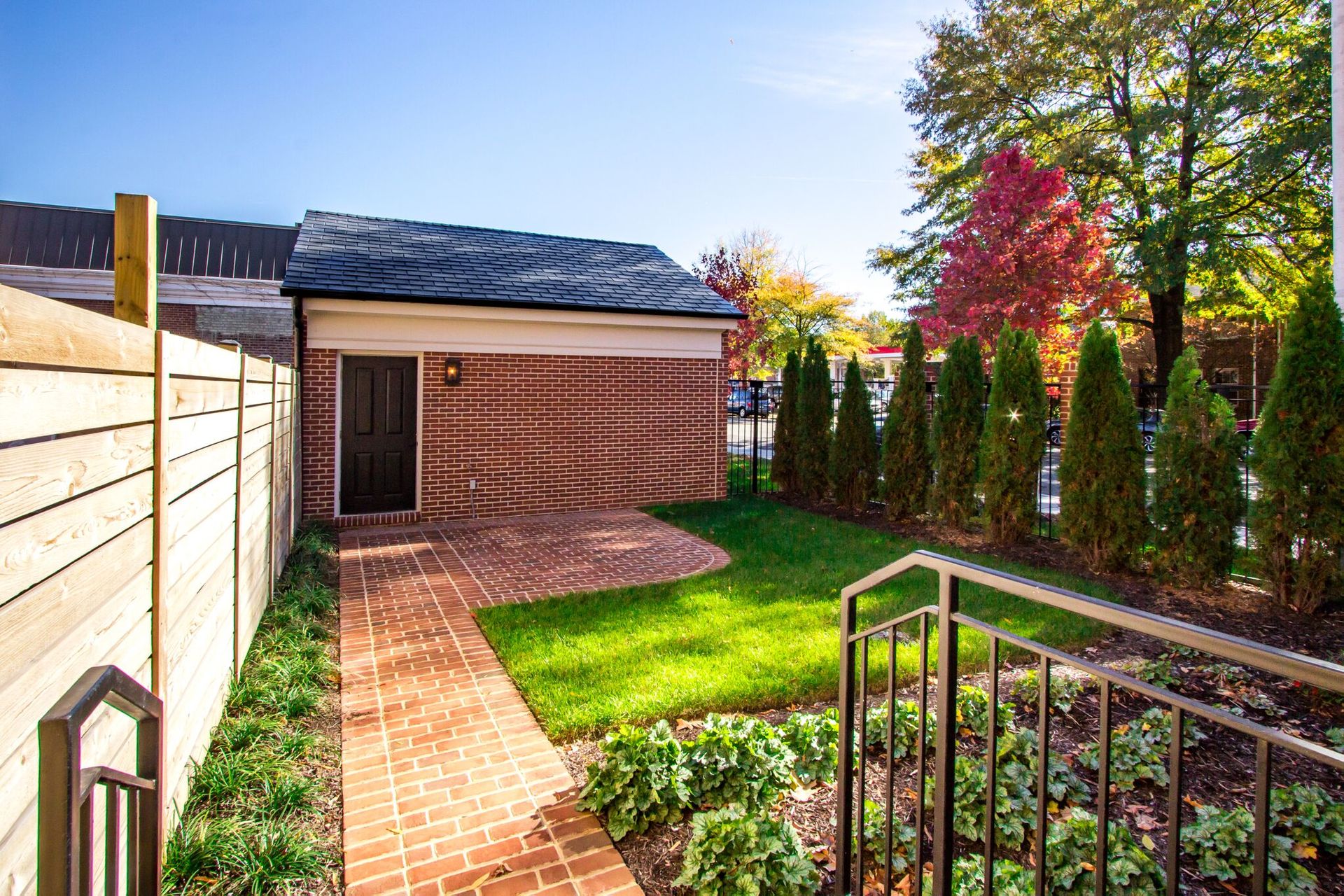 A brick walkway leads to a shed in the backyard of a house.