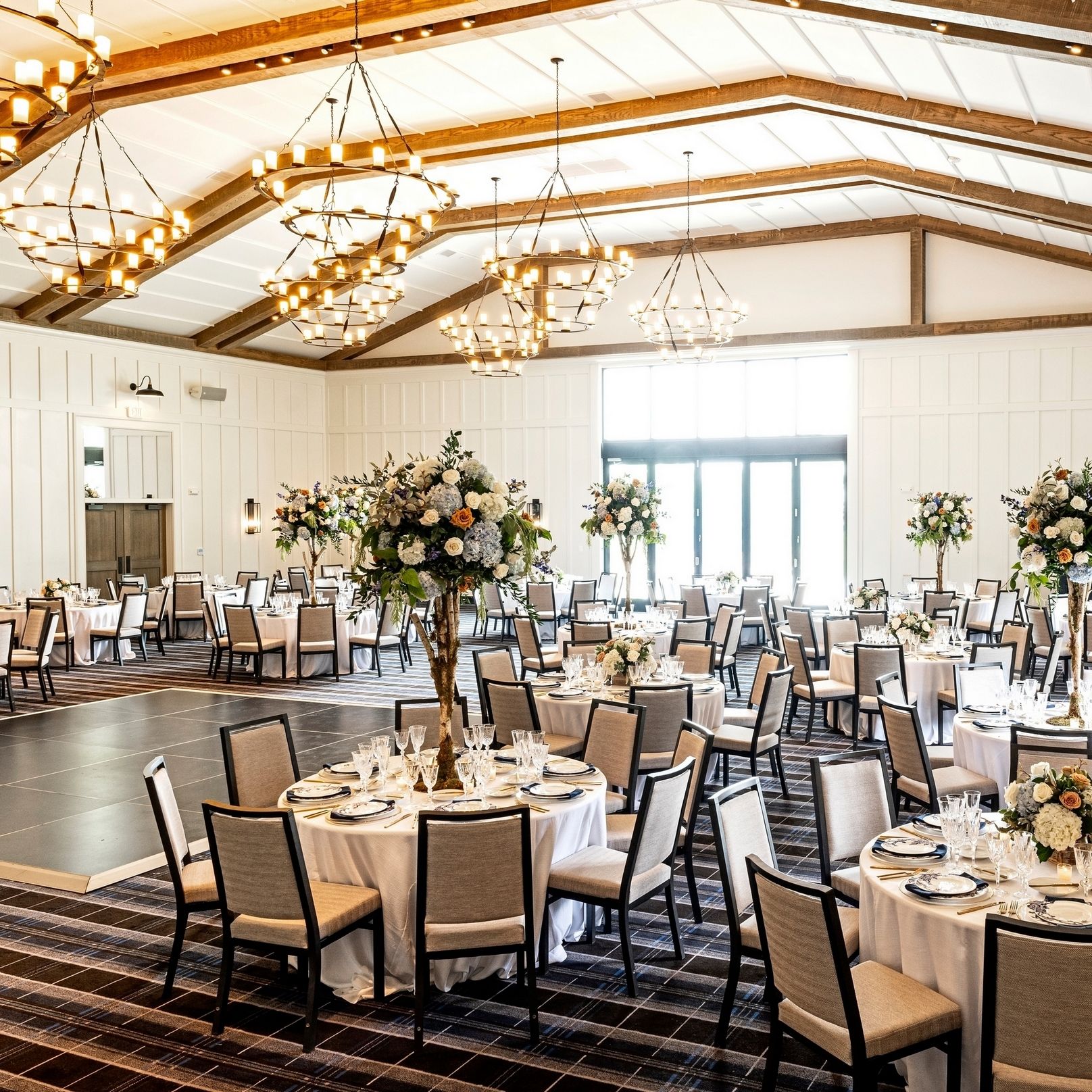A large room with tables and chairs set up for a wedding reception.