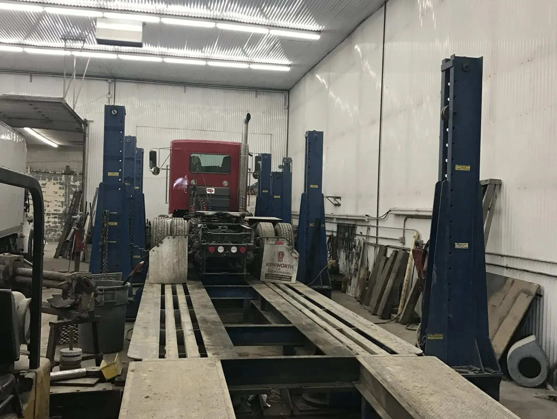 Auto shop with a red truck on a vehicle lift inside a white-walled garage