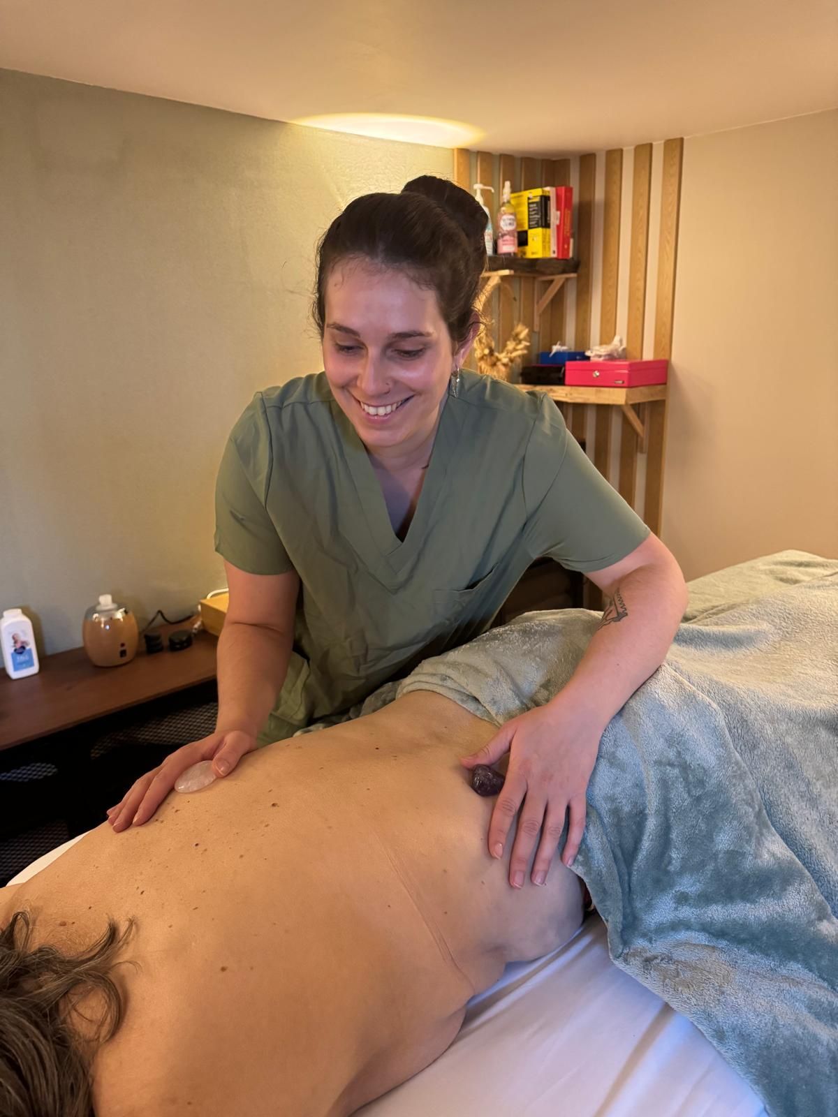 Un masseur s’occupant du dos d’un client dans une salle de soins à l’éclairage tamisé