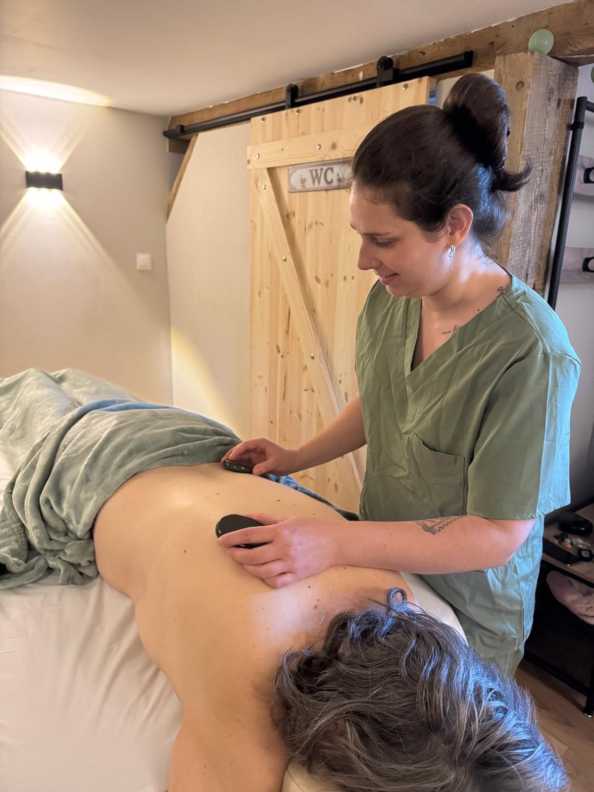 Un massothérapeute masse le dos d’un client dans une salle de soins de spa