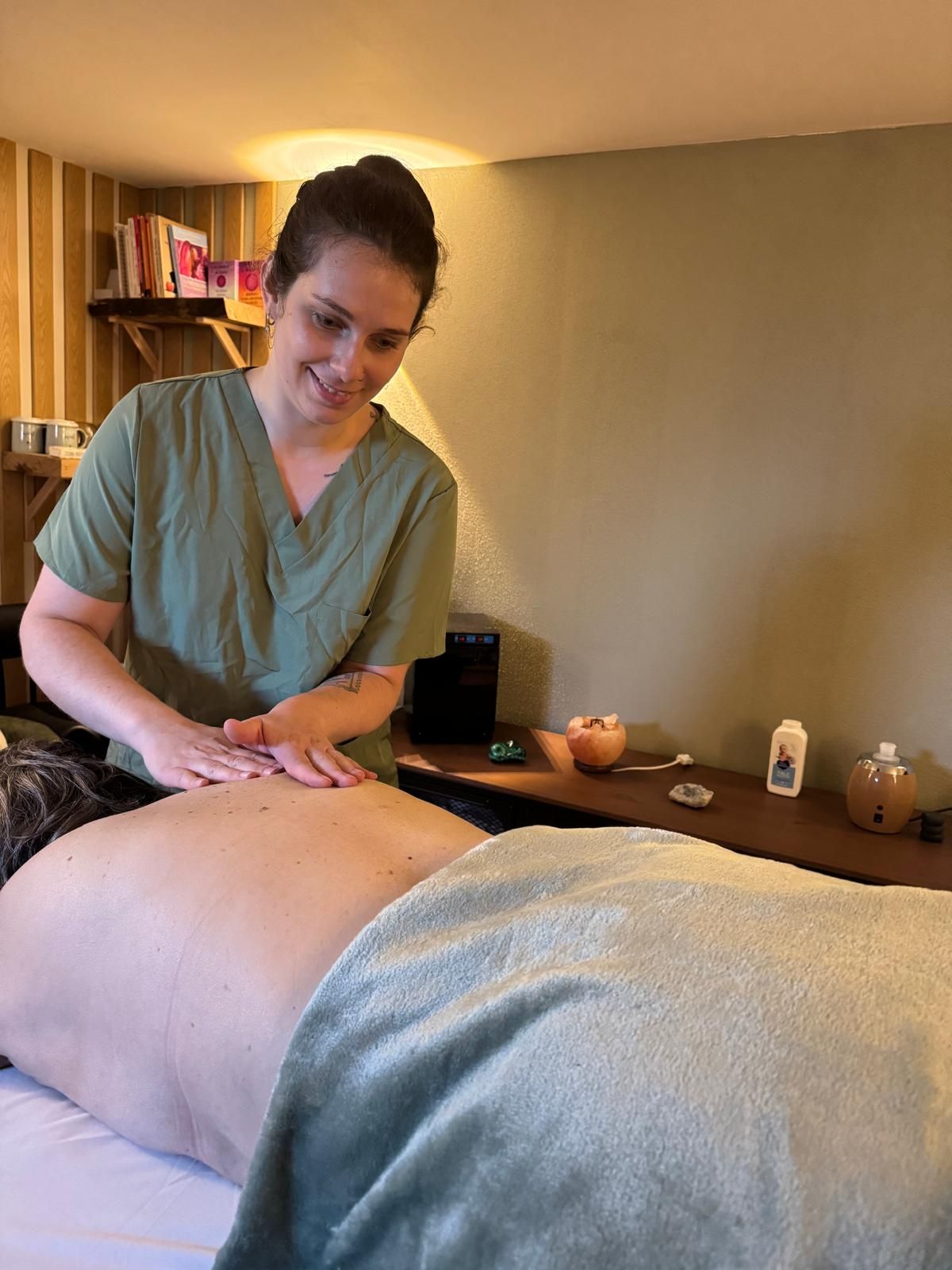 Masseur en train de masser le dos d’un client dans une salle de spa à l’éclairage chaleureux