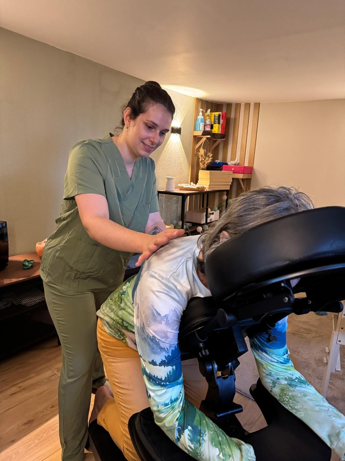 Un masseur en train de masser un client sur une table, dans une salle de soins chaleureuse