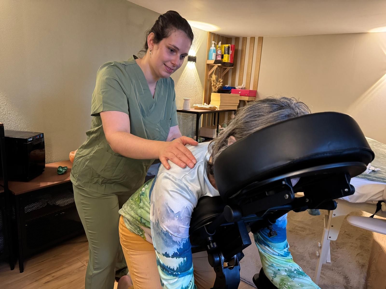 Un massothérapeute ajuste la position d’un client sur une table de massage, dans une salle de soins à domicile