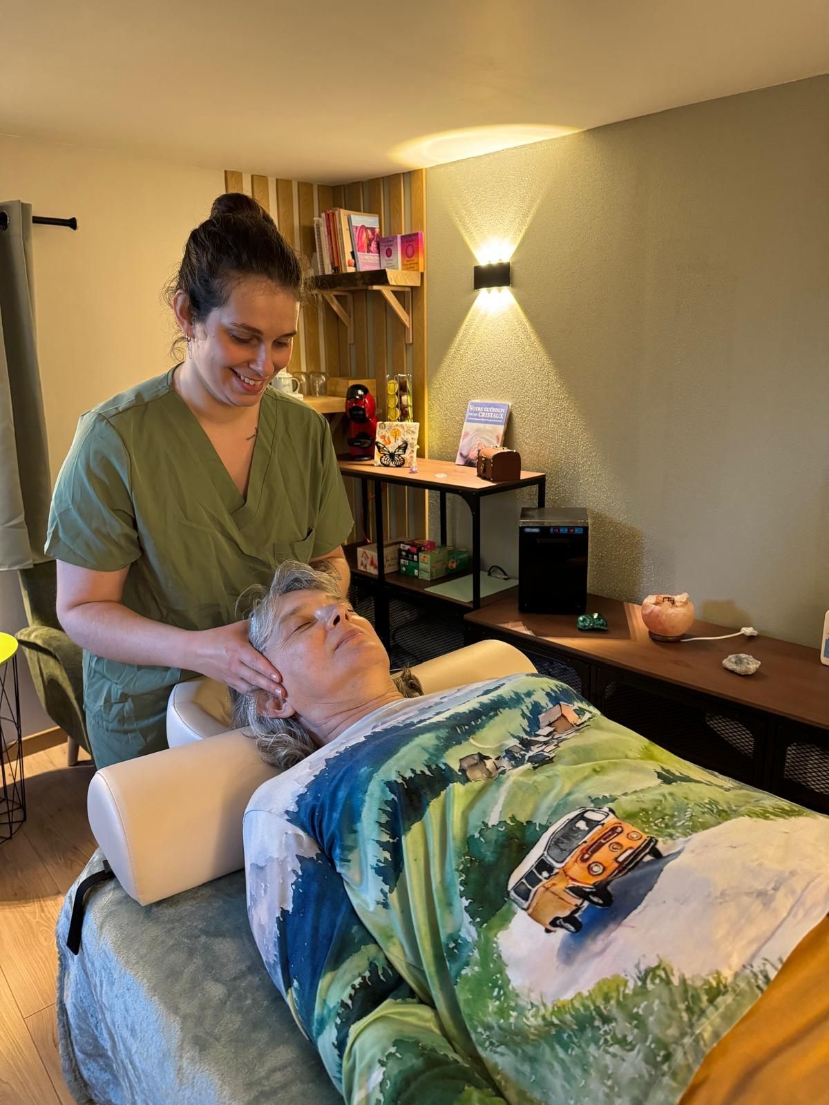 Un thérapeute prend doucement soin d’un client allongé dans une salle de massage à l’éclairage tamisé