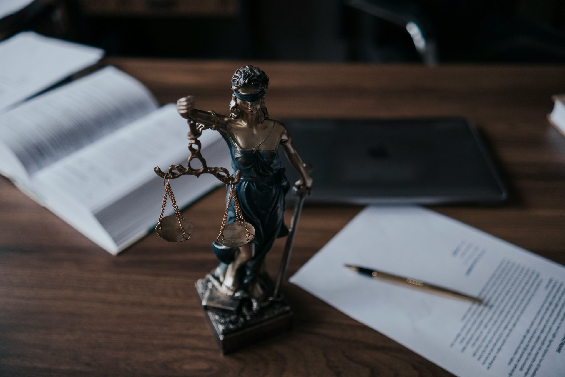 Lady Justice statue on a desk with legal papers and a pen, in a law office setting