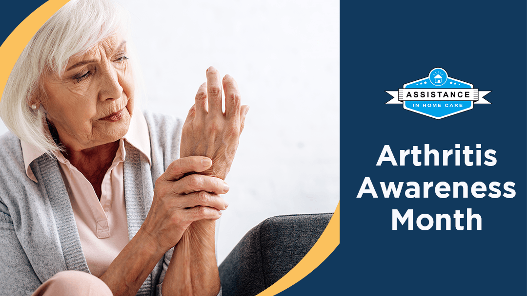 An older woman is sitting on a couch holding her wrist in pain.