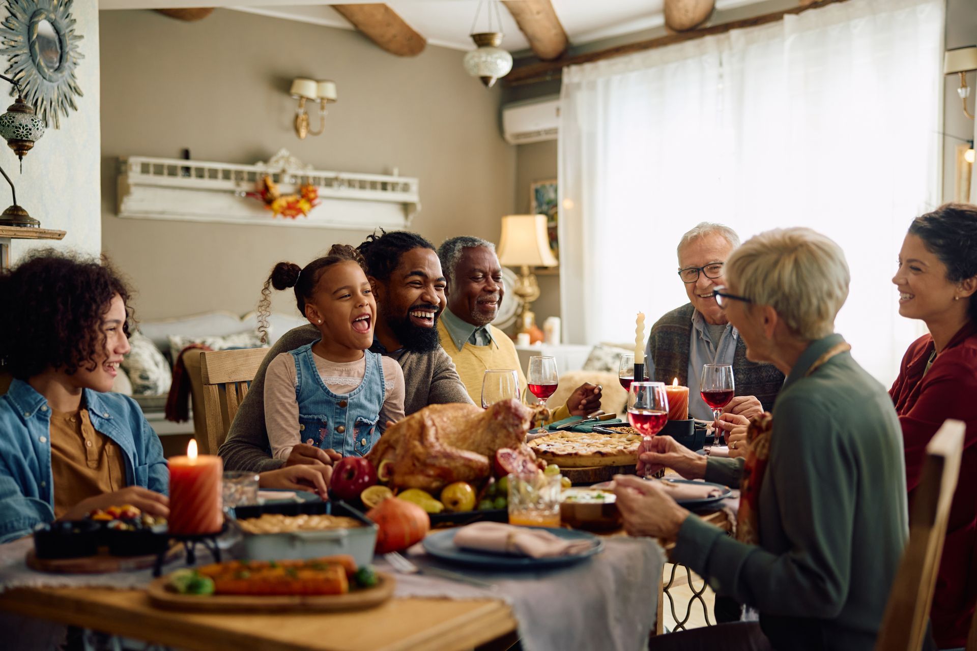 Family gathered around a table for a meal in a cozy, sunlit living room