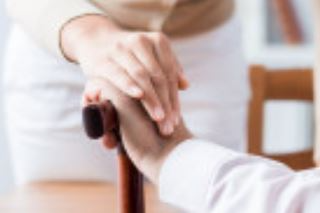 A person is holding another person 's hand while holding a cane.