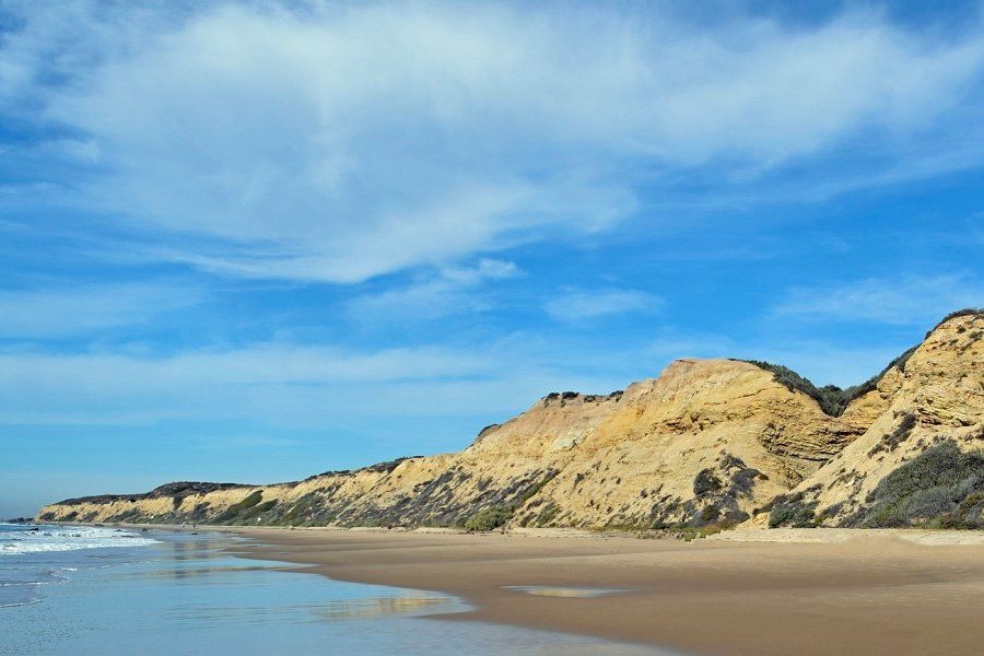 A beach with a mountain in the background and a blue sky