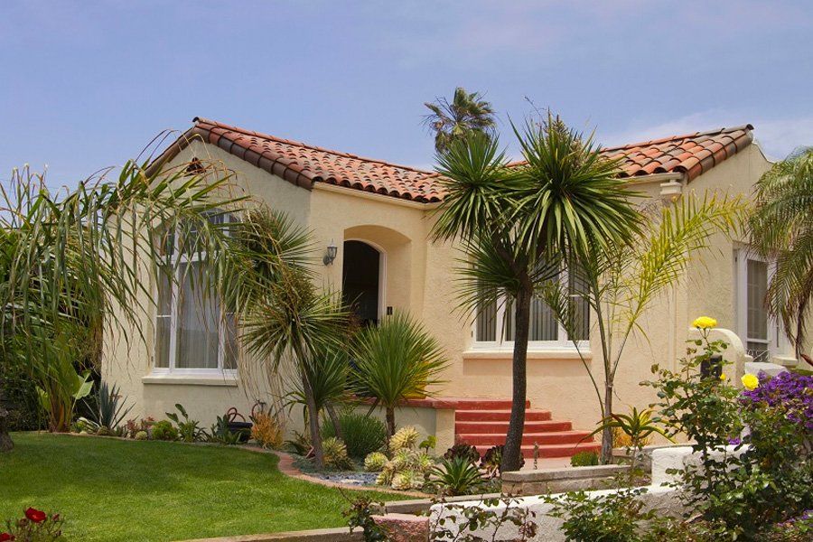 A white house with a red tile roof and palm trees in front of it