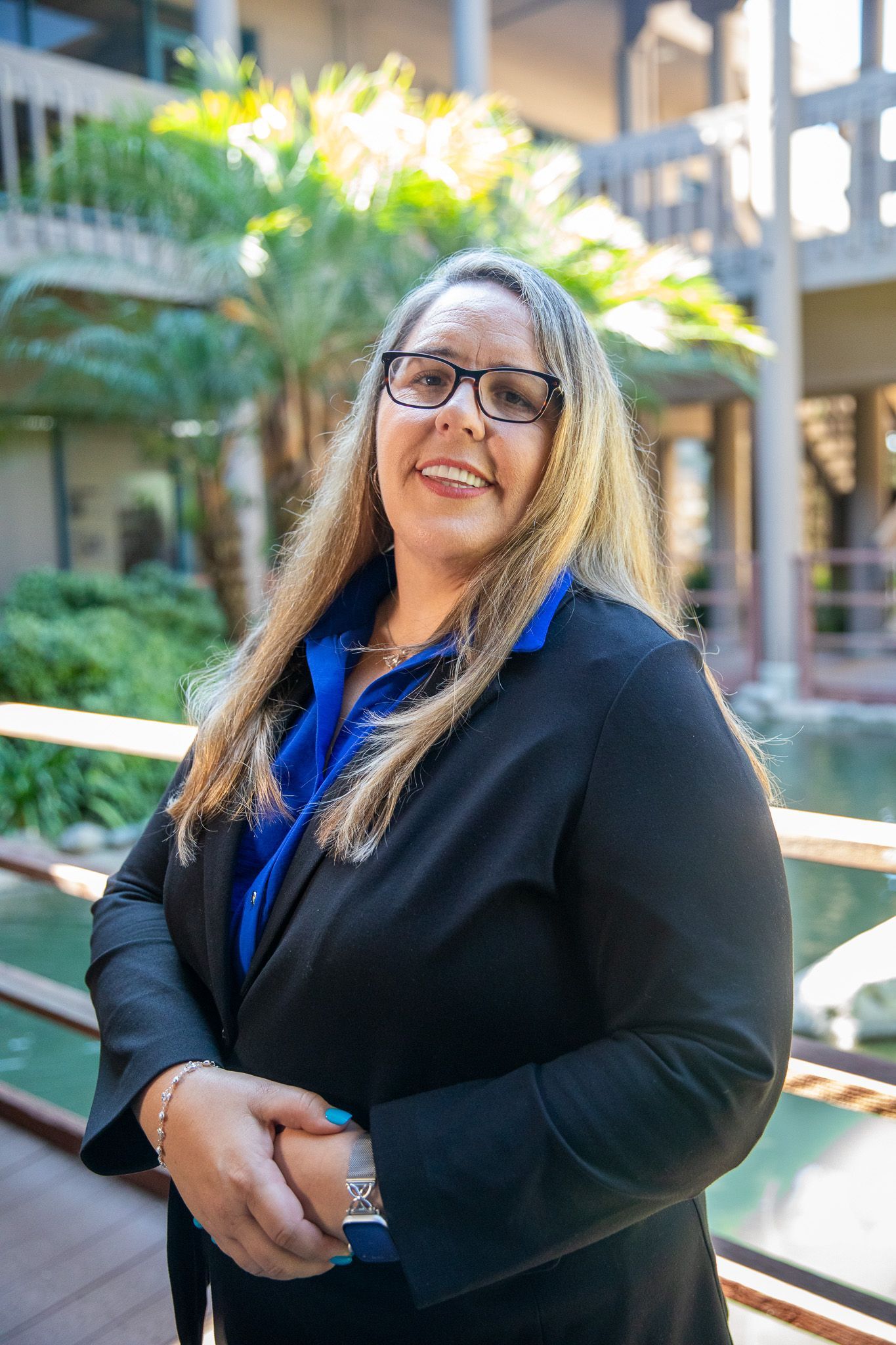 A woman wearing glasses and a black jacket is smiling for the camera.