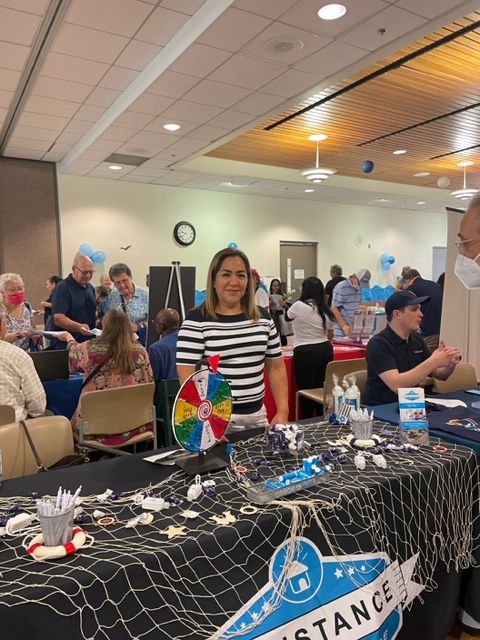 A woman is standing in front of a table that says assistance