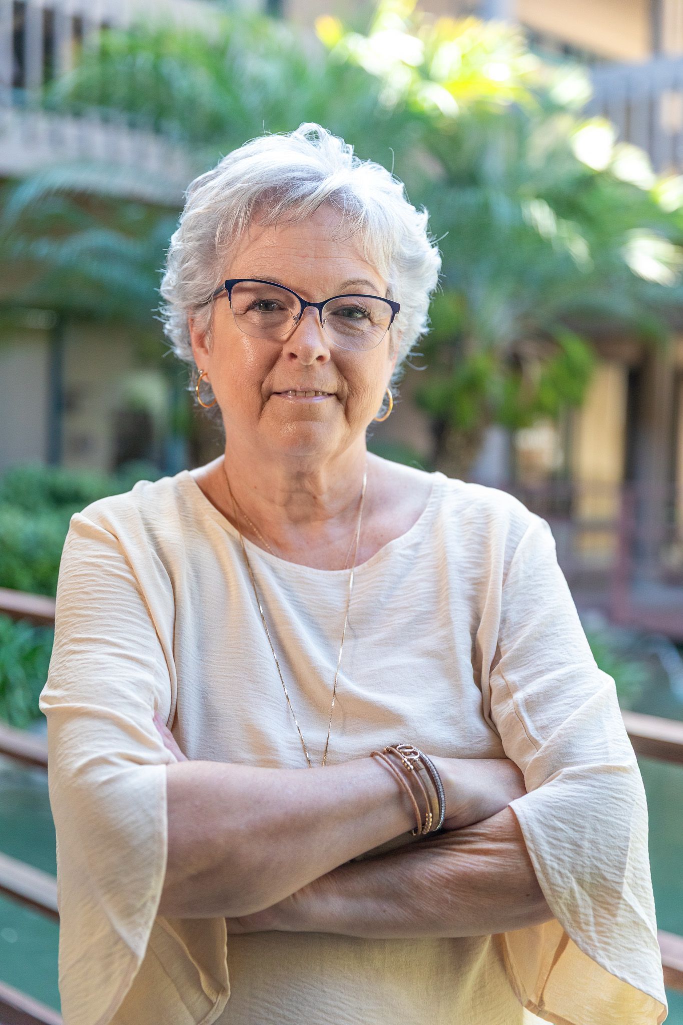 A woman wearing glasses and a blue shirt is smiling for the camera.