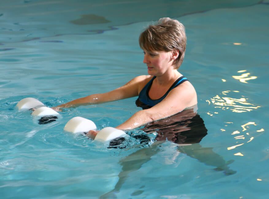 A woman is holding dumbbells in a swimming pool