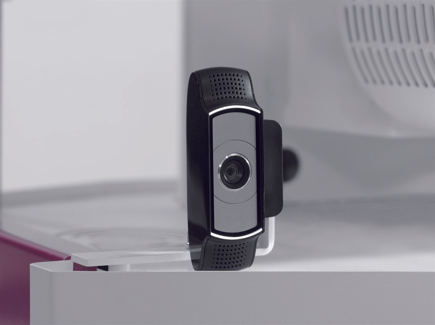 A webcam is sitting on a table next to a monitor.