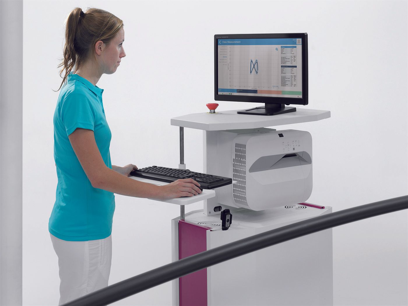 A woman is standing at a desk with a computer on it