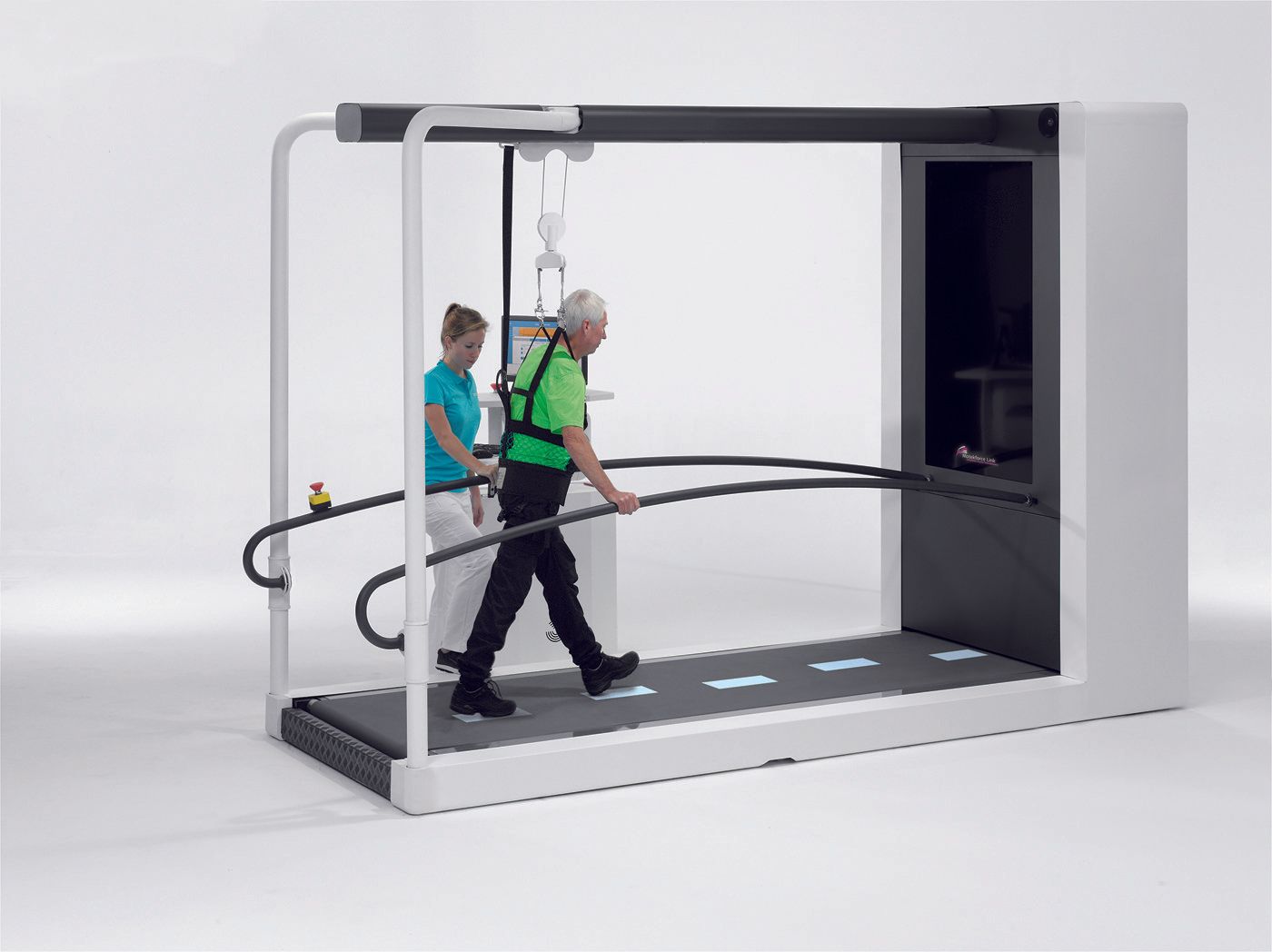 A man is walking on a treadmill with a woman standing behind him.