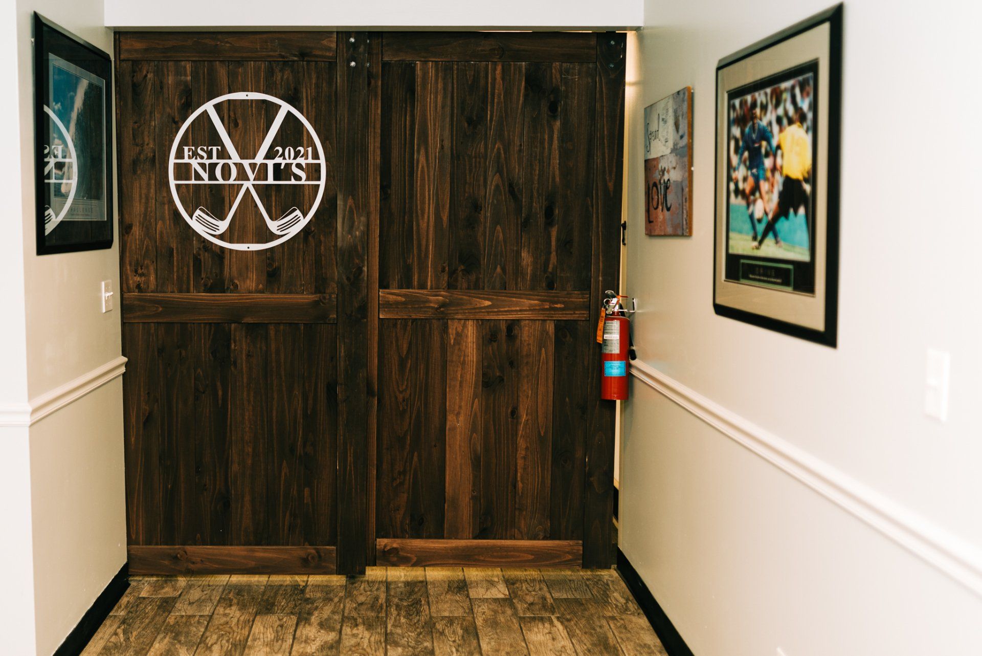 A hallway with a wooden door and a fire extinguisher.