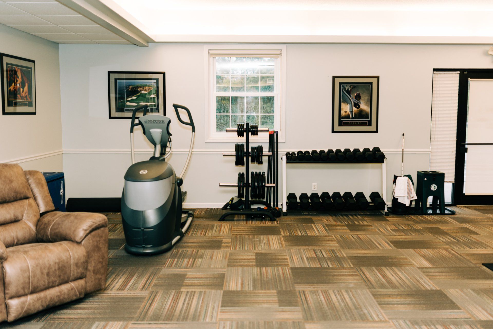 A living room with a couch , exercise machine , and dumbbells.