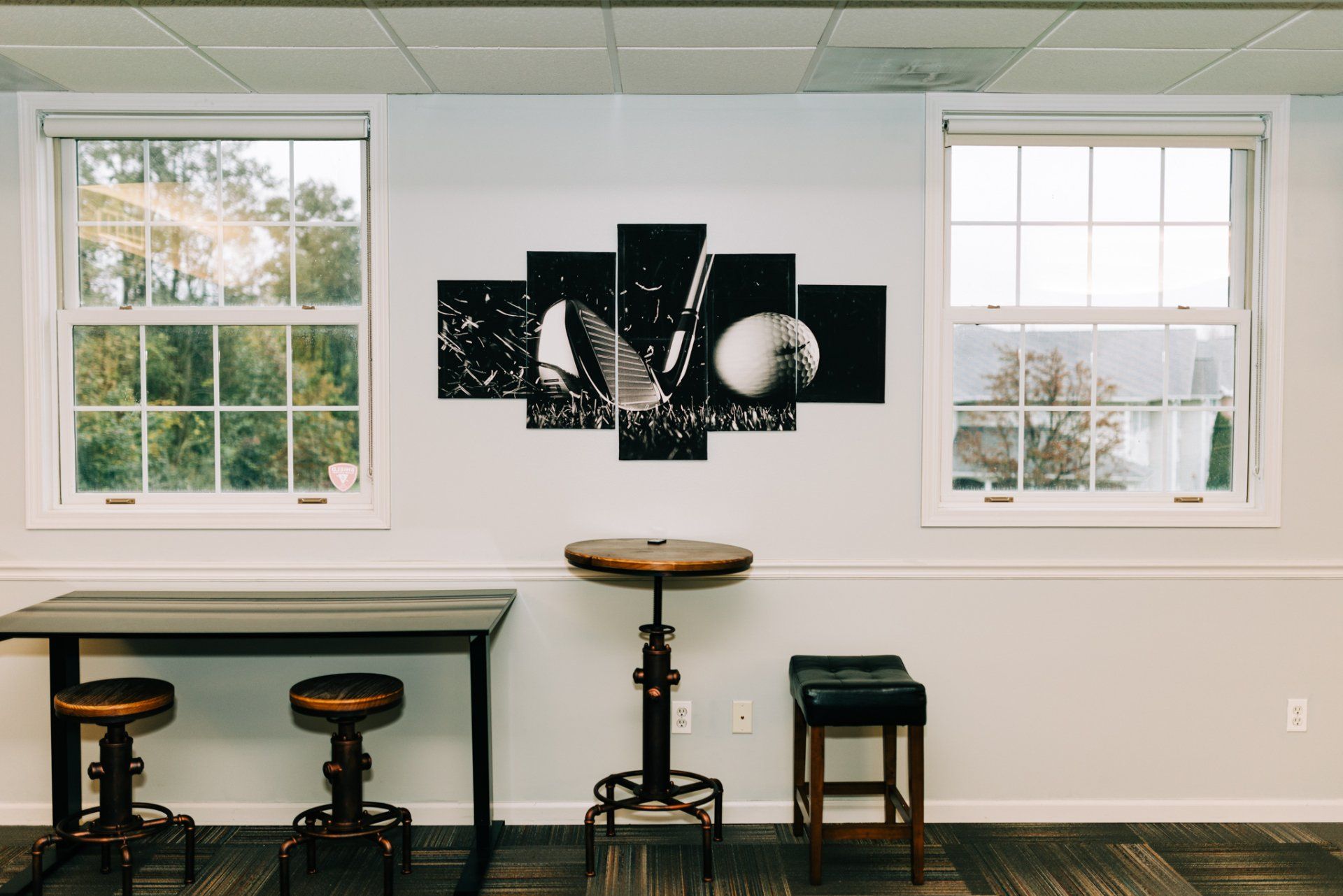 A room with a table and stools and a painting on the wall.