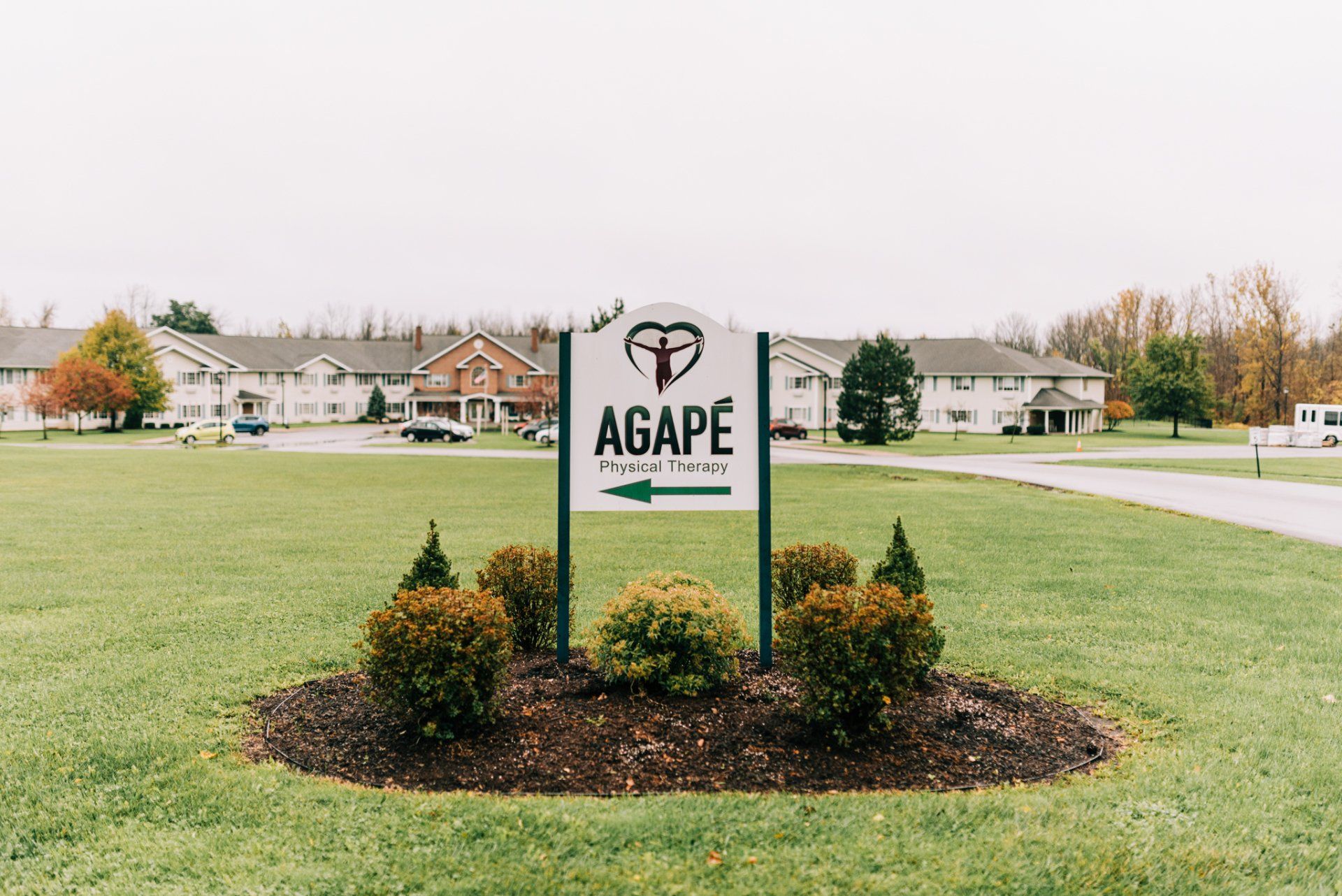 A sign for agape is in the middle of a grassy field.