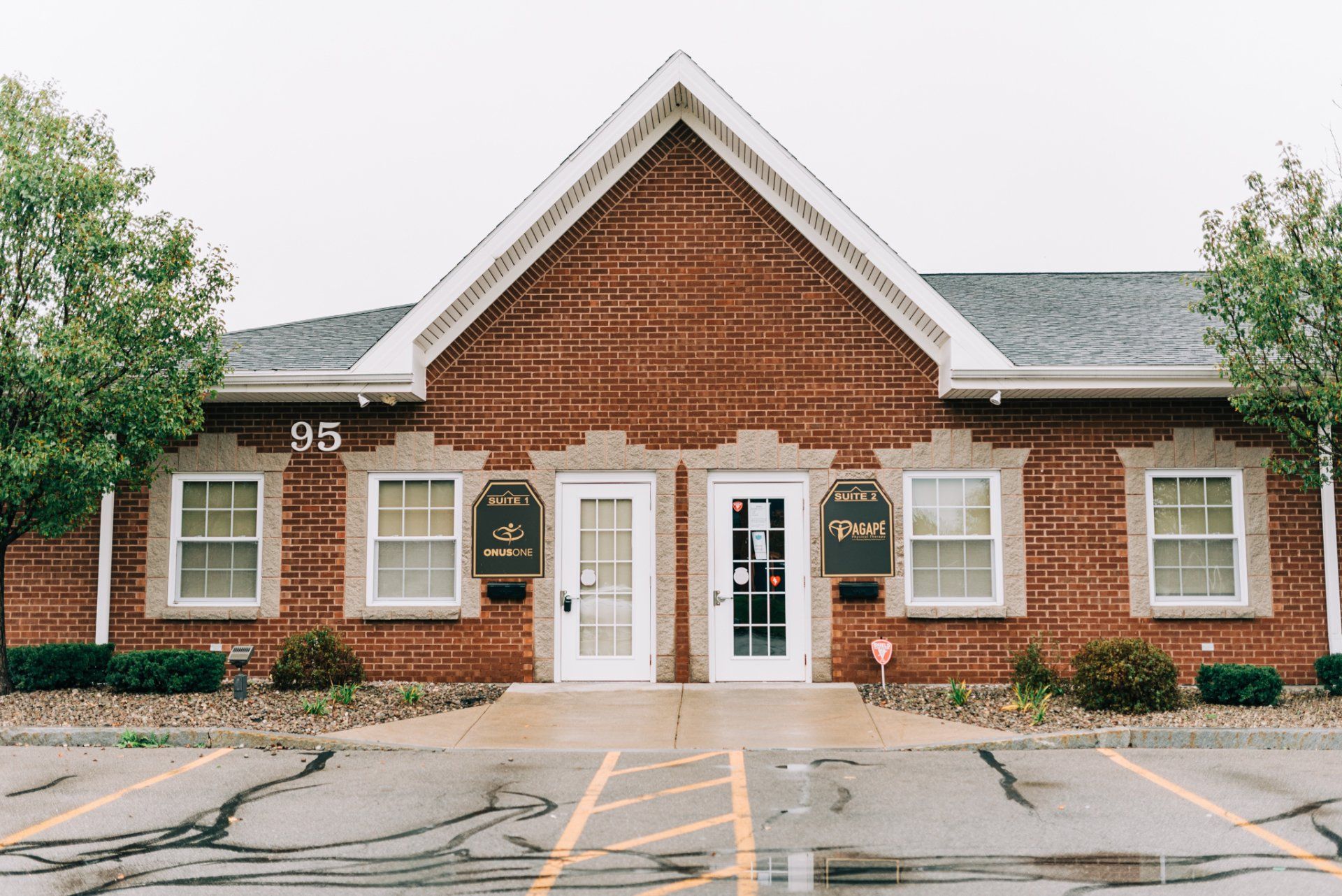 A brick building with a lot of windows and a parking lot in front of it.