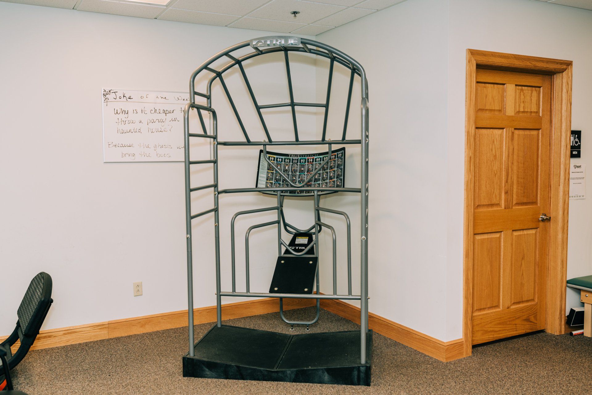 A basketball hoop is sitting in the corner of a room next to a door.