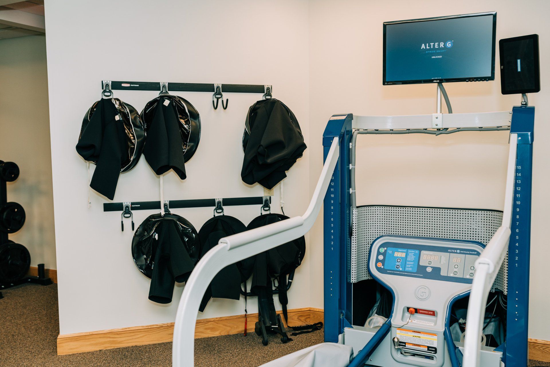 A gym with a treadmill and a monitor on the wall.