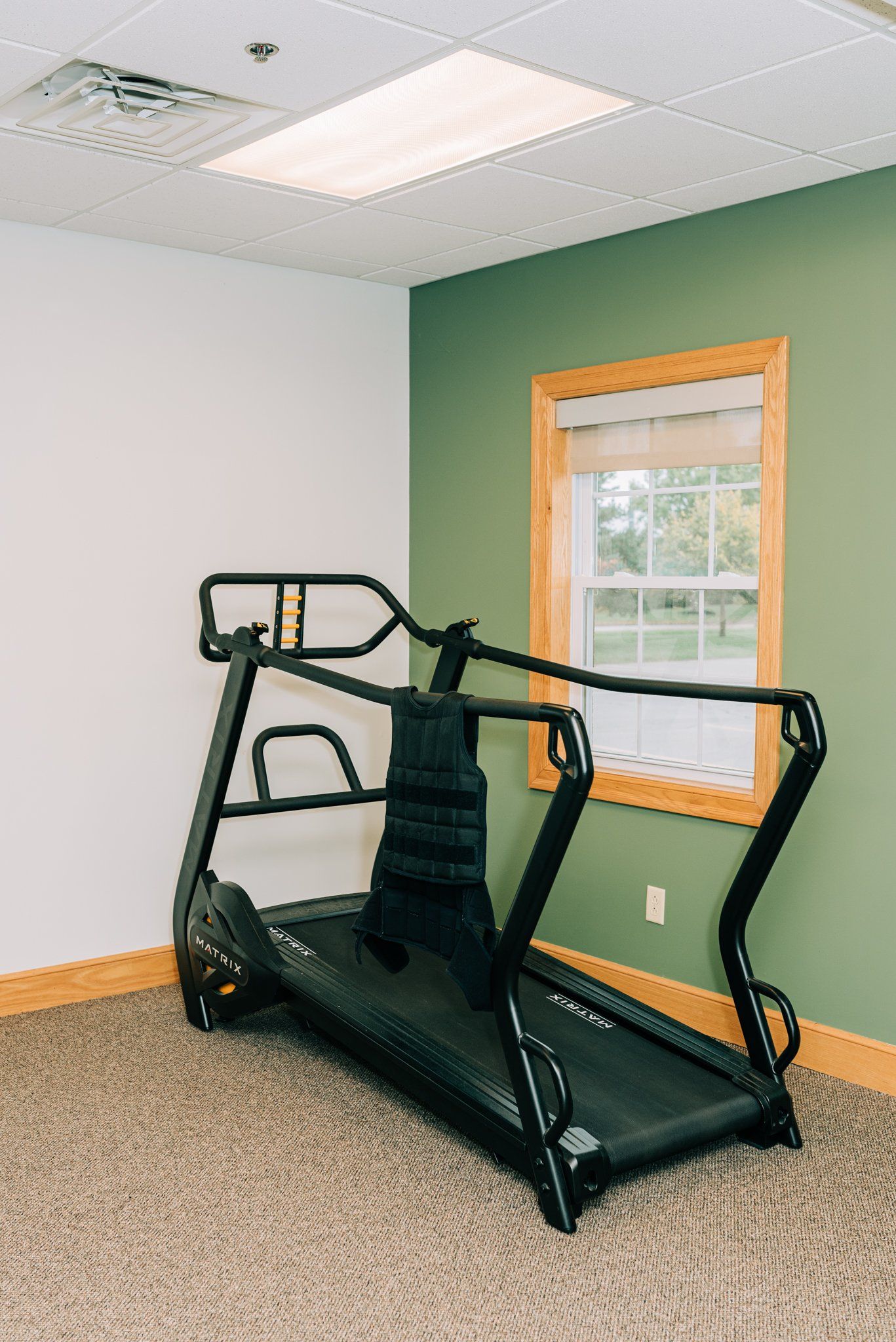 A treadmill is sitting in a room next to a window.