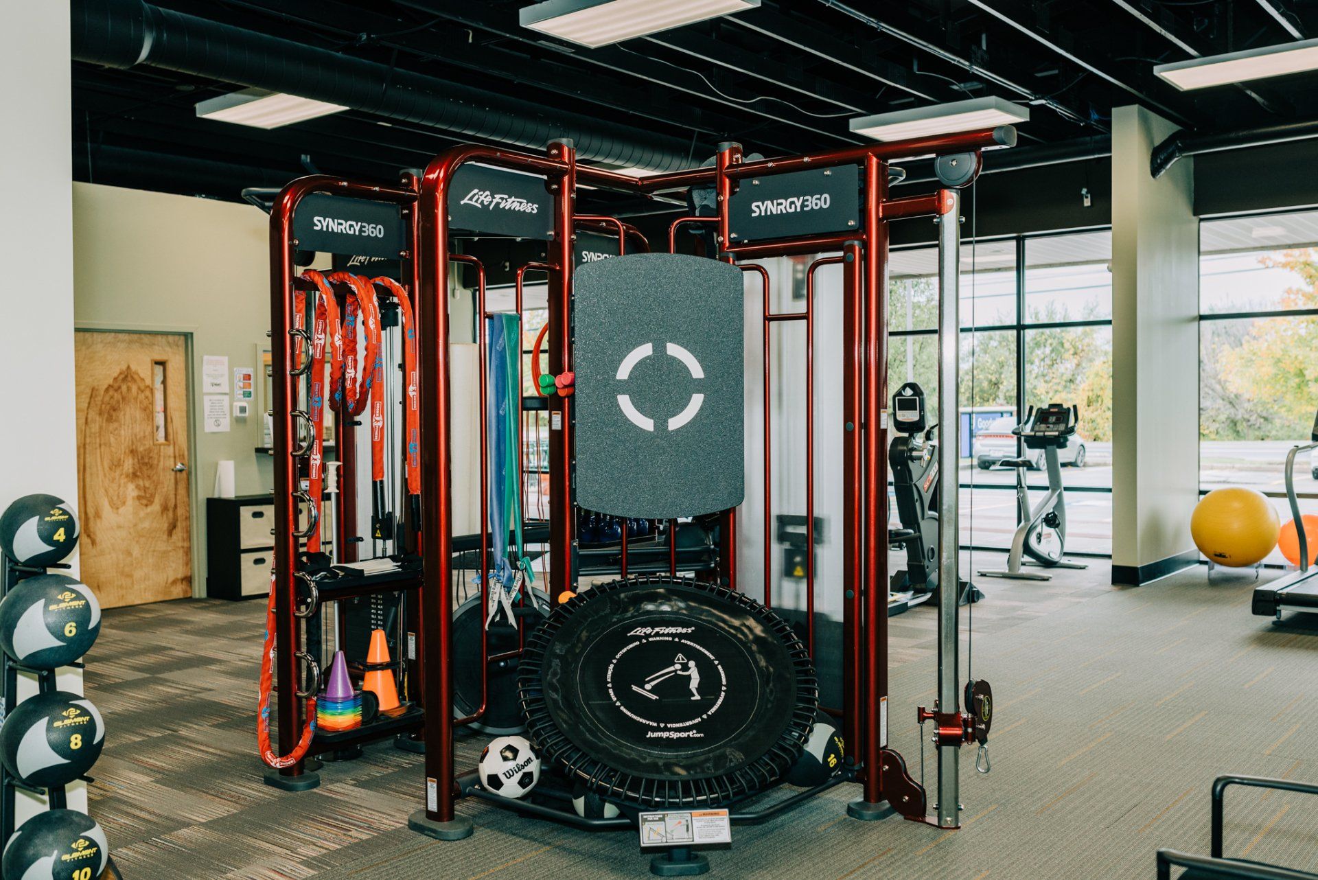 A gym with a lot of equipment and a large tire in the middle.