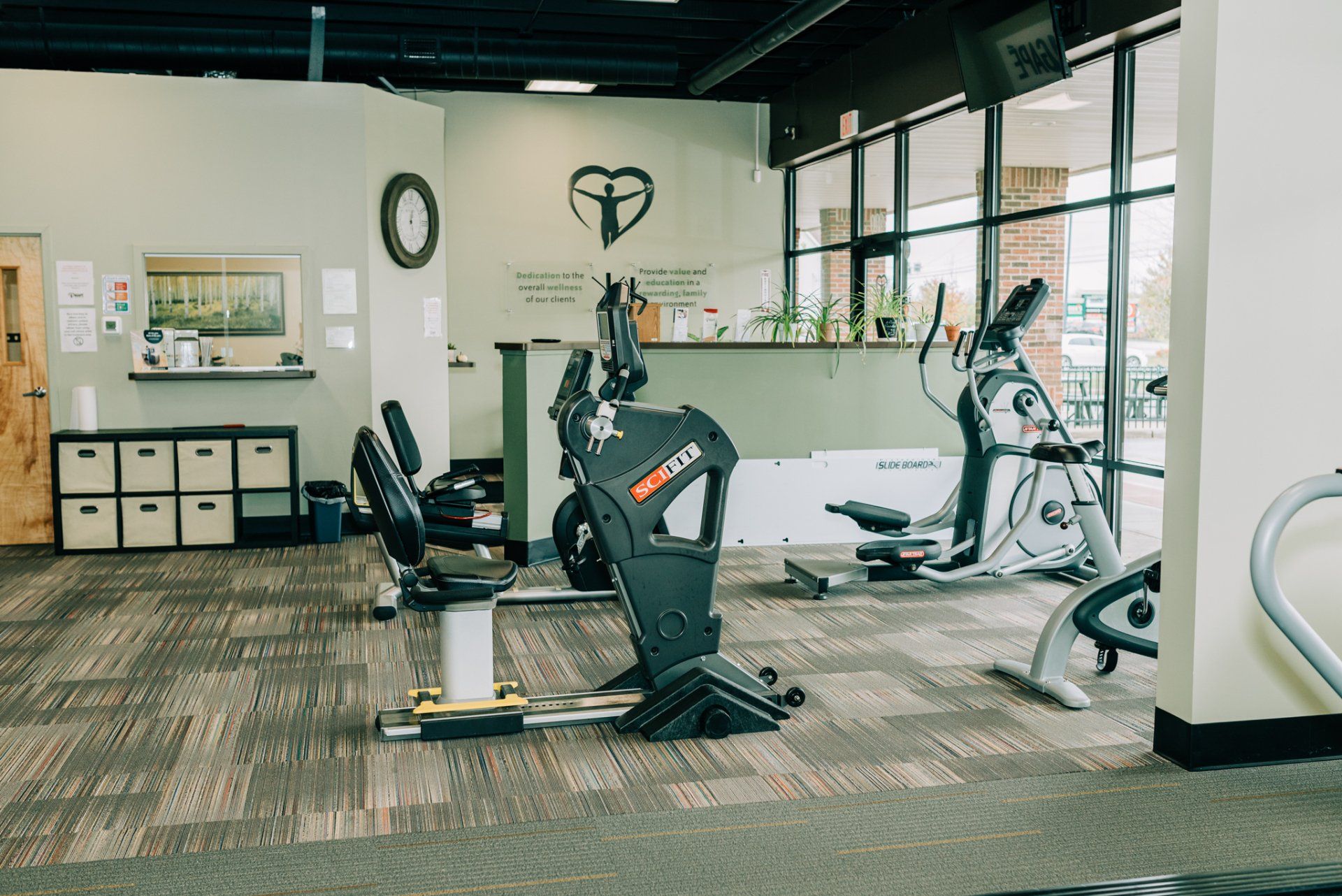 A gym with a lot of exercise equipment and a heart on the wall.