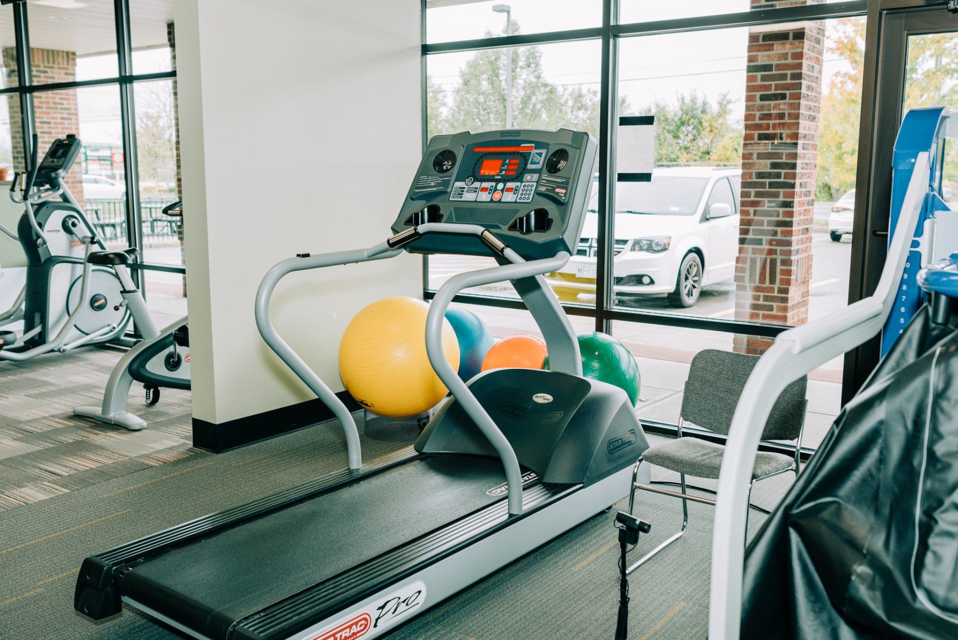 A treadmill is sitting in a gym next to a chair.
