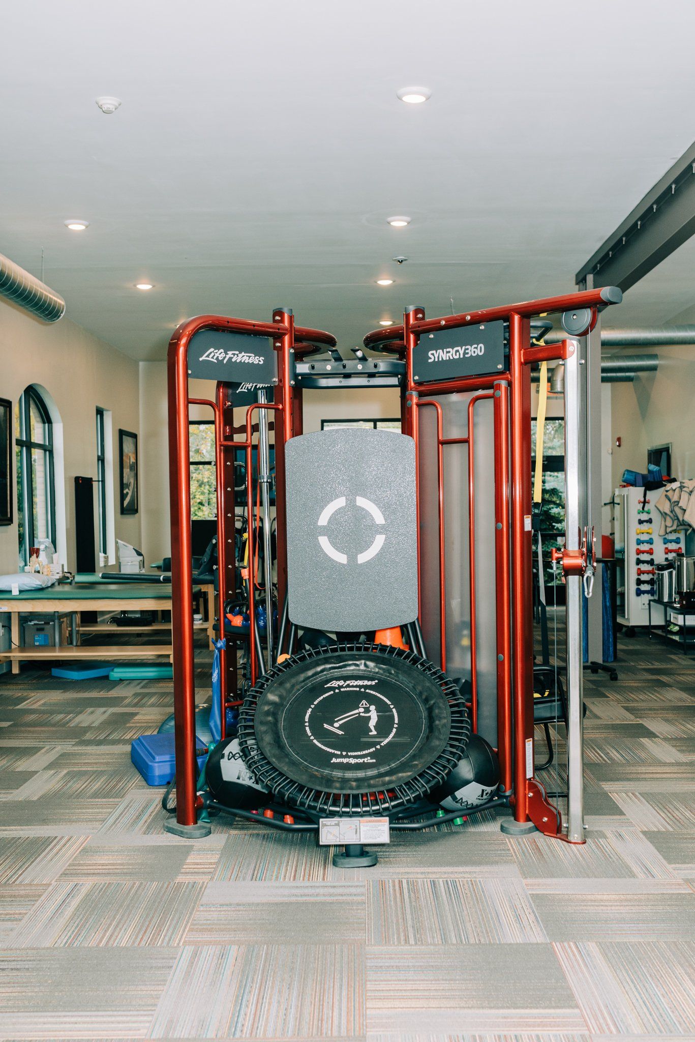A gym with a lot of equipment and a trampoline on the floor.