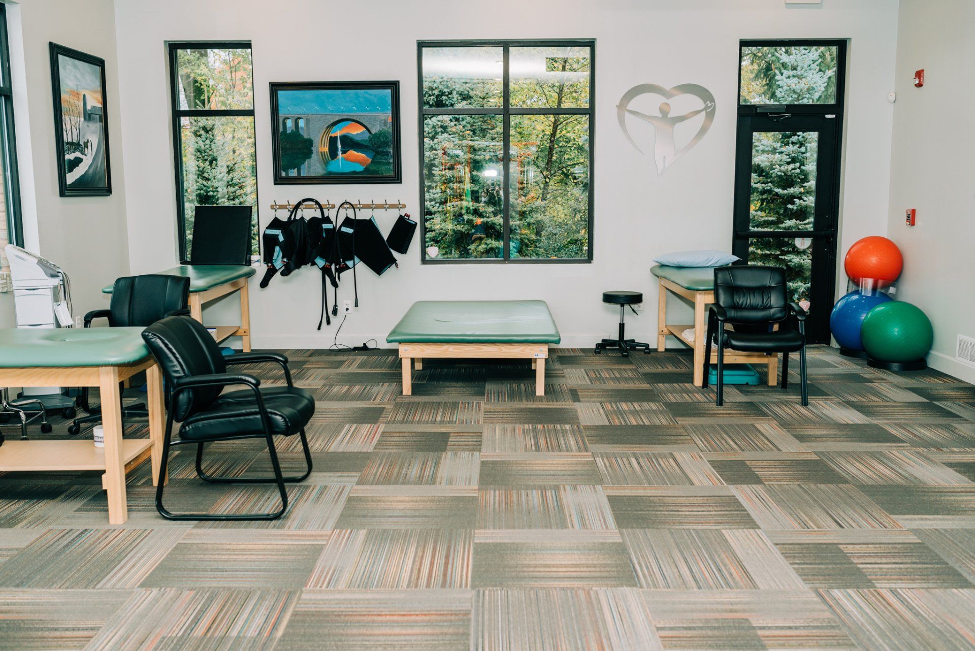 A therapy room with tables , chairs , and exercise balls.