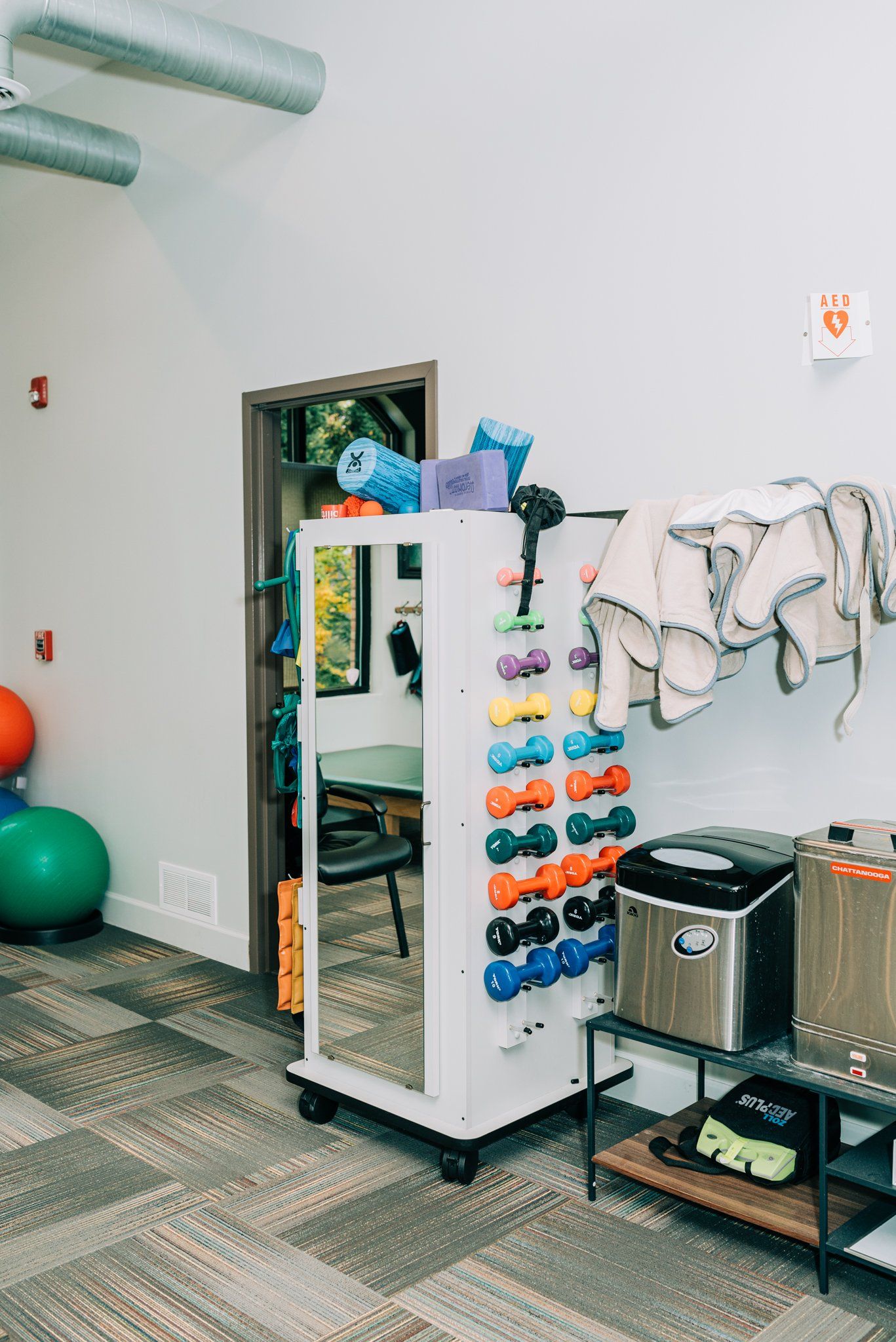 A room with a lot of dumbbells and a mirror.