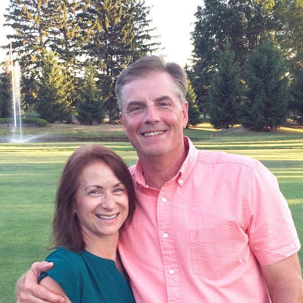 A man in a pink shirt is standing next to a woman in a green shirt