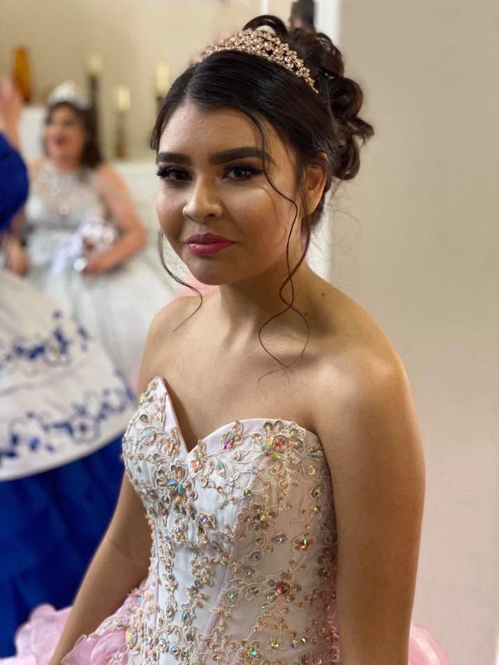 Woman in a strapless white floral gown at a formal event, smiling toward the camera.