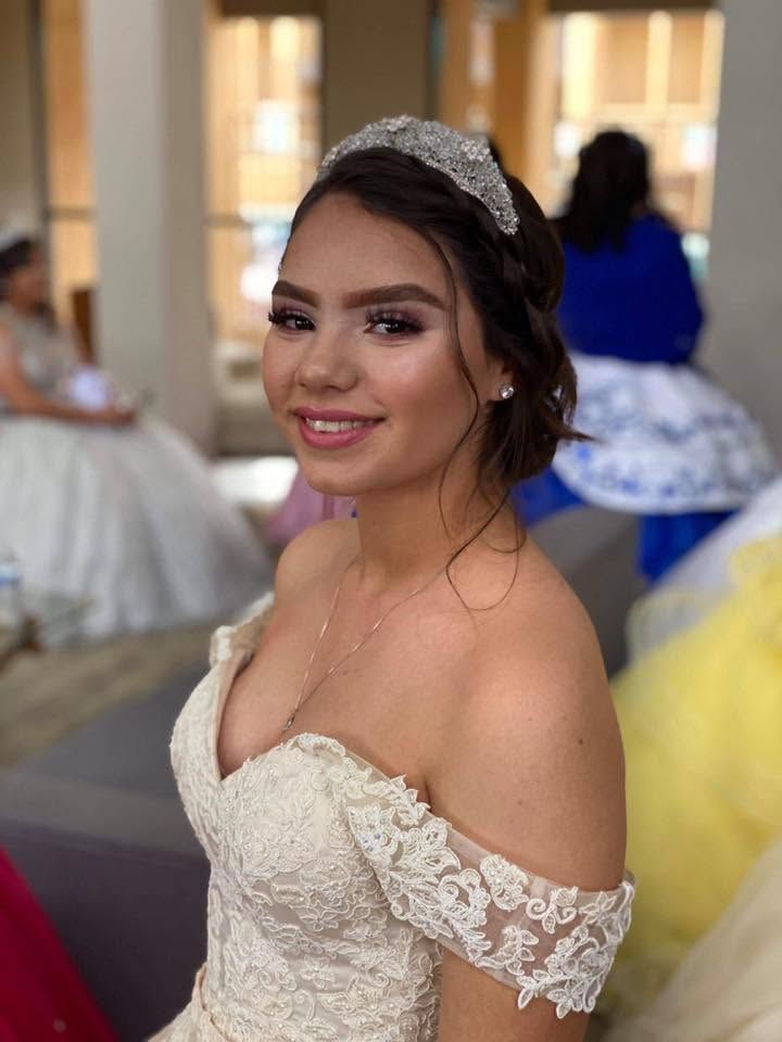 Smiling woman in a white off-shoulder gown and tiara at a formal event