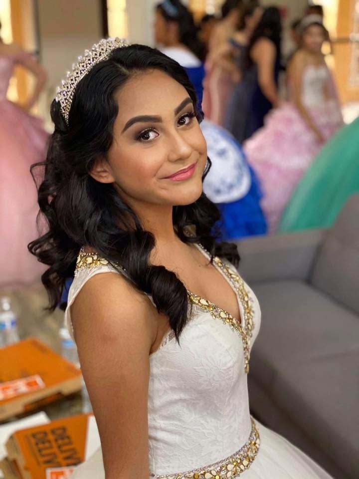 Woman in a white embellished gown smiling at a formal event, with blurred guests in the background