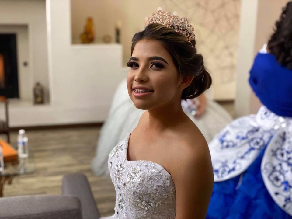 Bride in a white beaded gown and veil smiling in a wedding venue