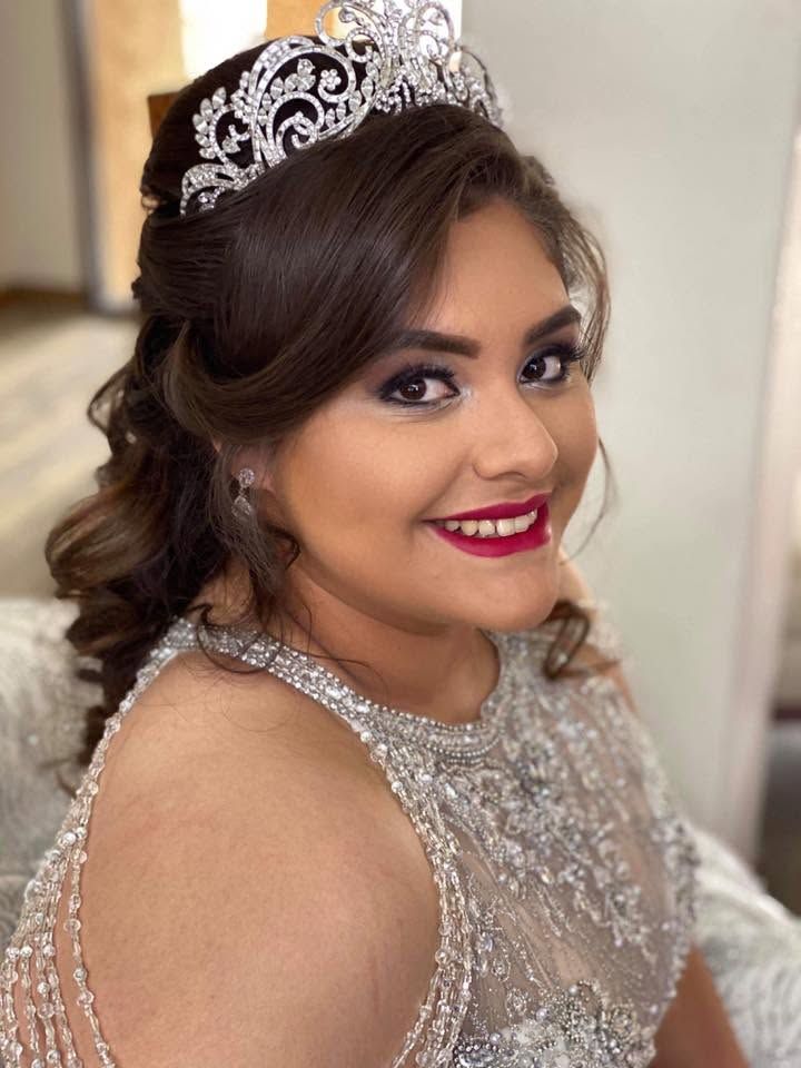 Young woman in a silver dress and tiara smiling in a formal portrait