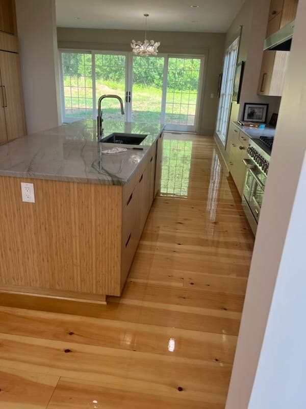 A kitchen with hardwood floors , a sink , and sliding glass doors.