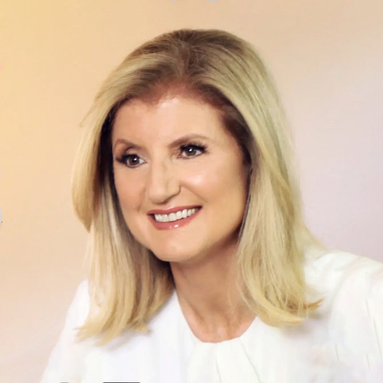 Smiling blonde woman in a white top against a soft pink background