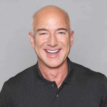 Smiling bald man in a black polo shirt against a gray background