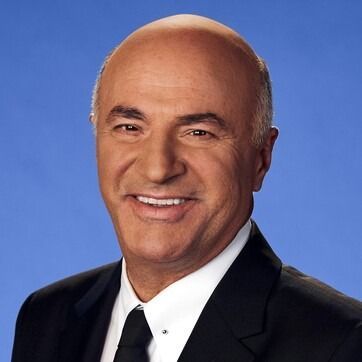 Smiling bald man in a black suit and tie against a blue background