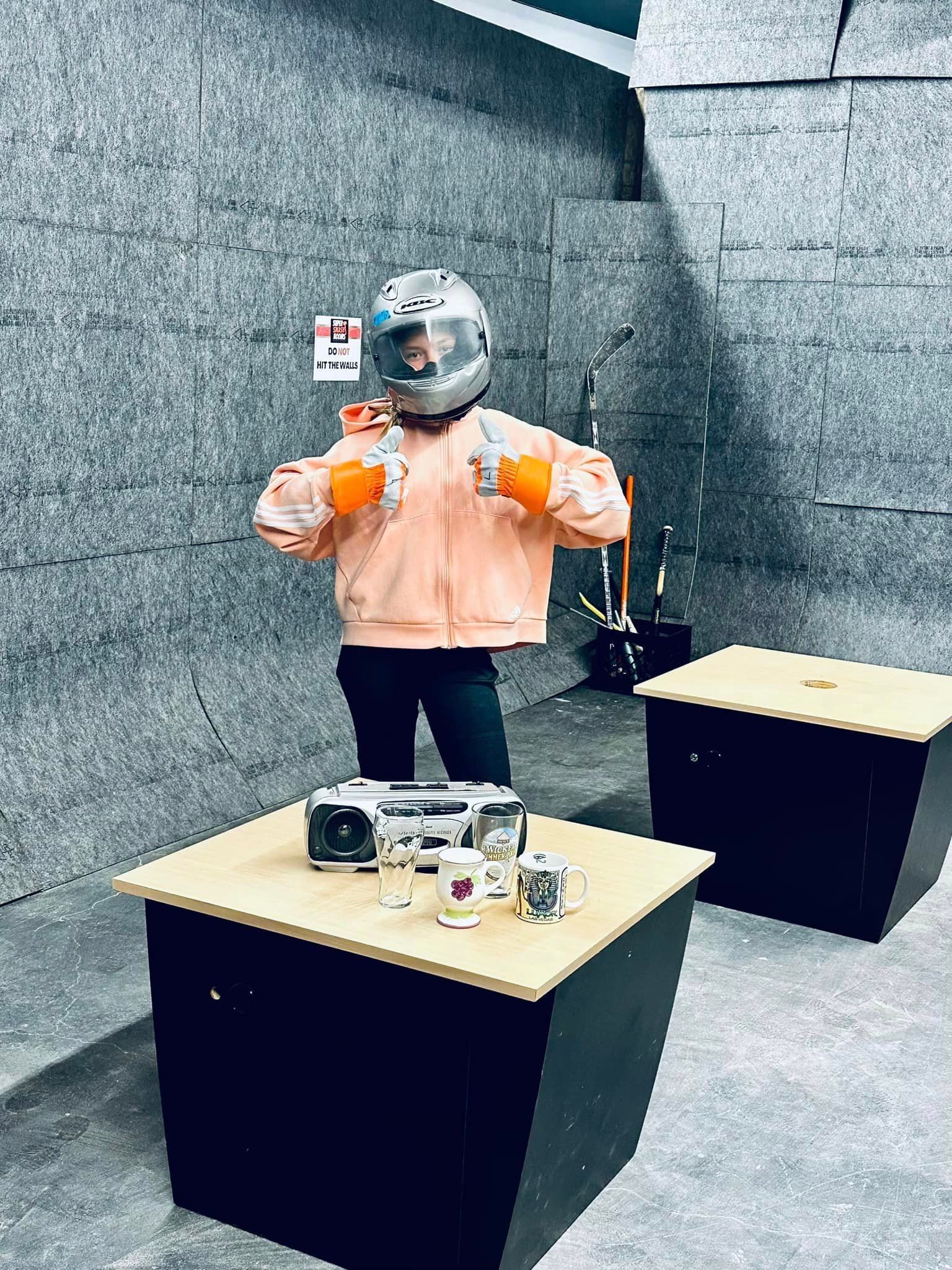 A person wearing a helmet and boxing gloves is standing next to a table.