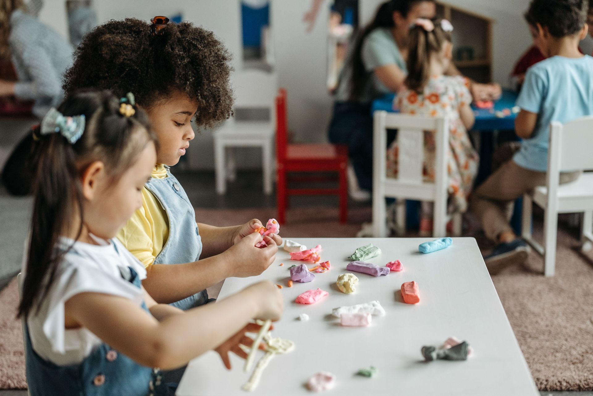 Children making crafts at a classroom table with colorful paper and supplies