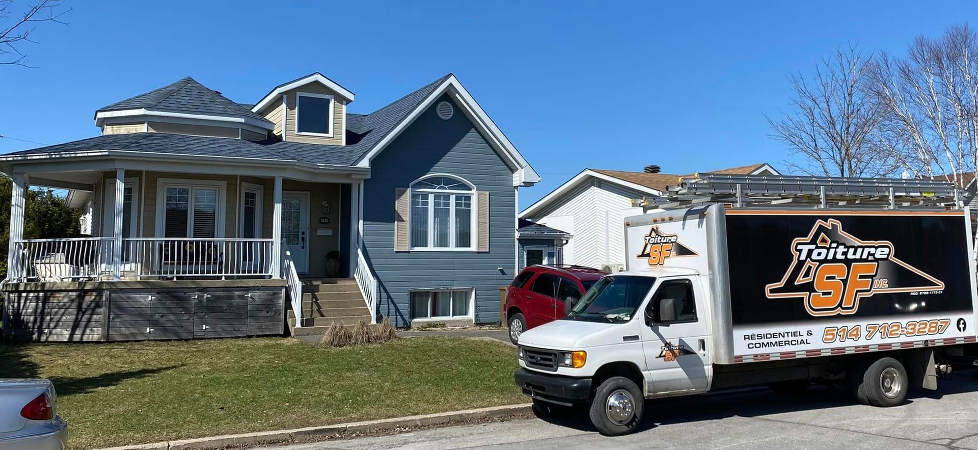 Maison avec un toit et un bardage bleus, avec un camion blanc portant l'inscription « Toiture 85 ».