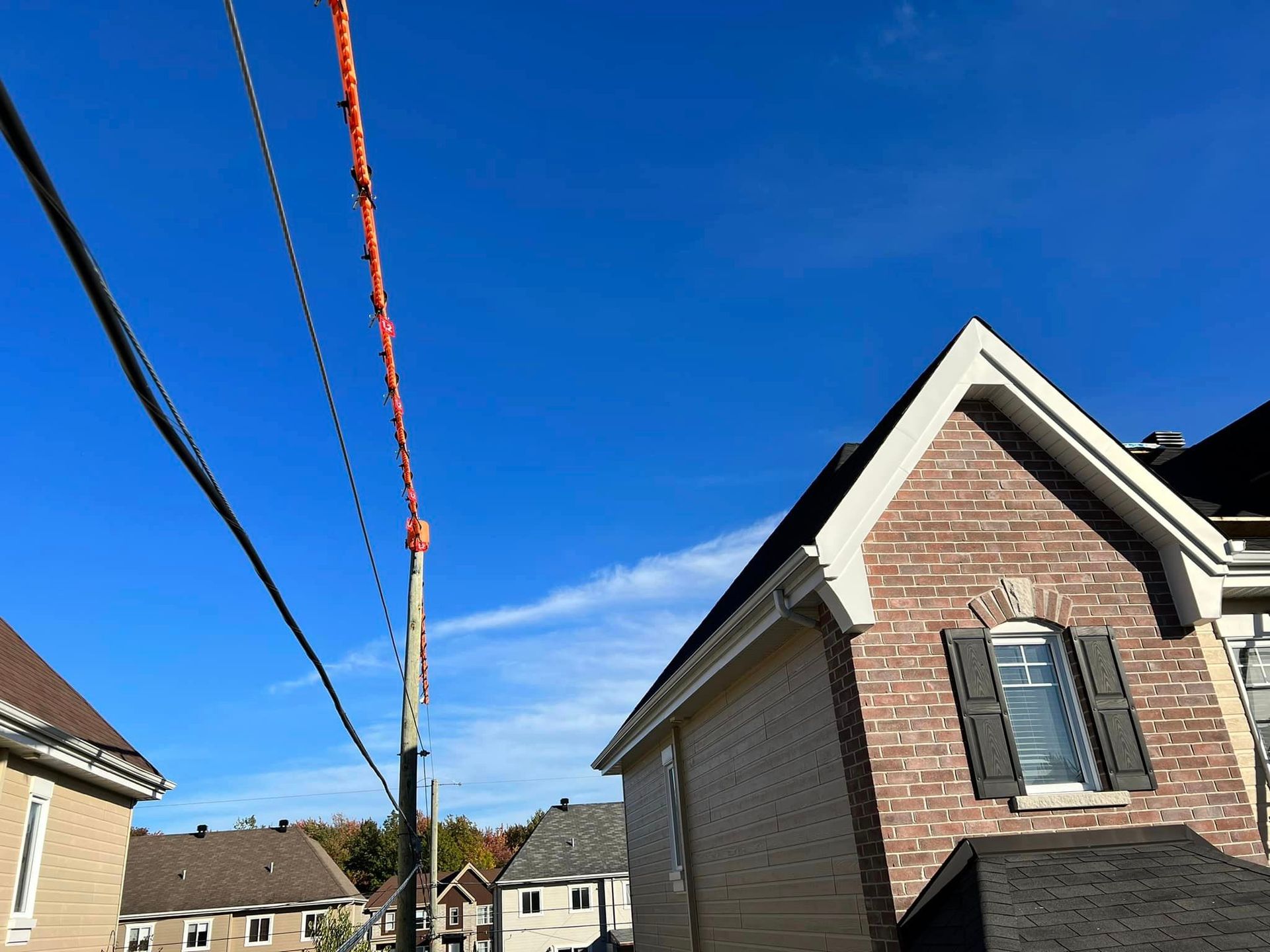 Bâtiment en briques avec une fenêtre sombre, lignes électriques se détachant sur un ciel bleu clair.